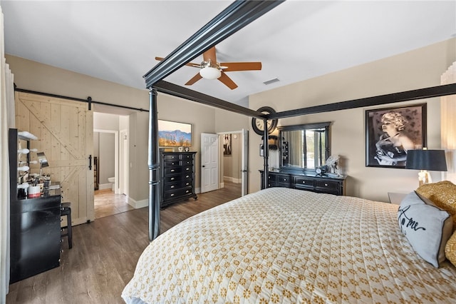 bedroom with hardwood / wood-style floors, a barn door, and ceiling fan