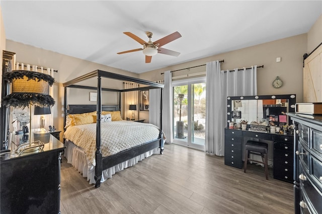 bedroom featuring wood-type flooring, a barn door, access to outside, and ceiling fan