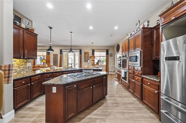 kitchen featuring sink, decorative light fixtures, a center island, appliances with stainless steel finishes, and kitchen peninsula