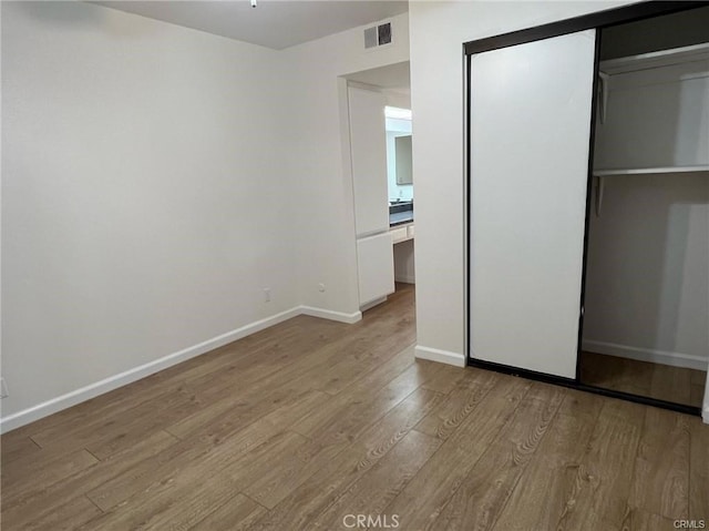 unfurnished bedroom featuring built in desk, a closet, and light wood-type flooring