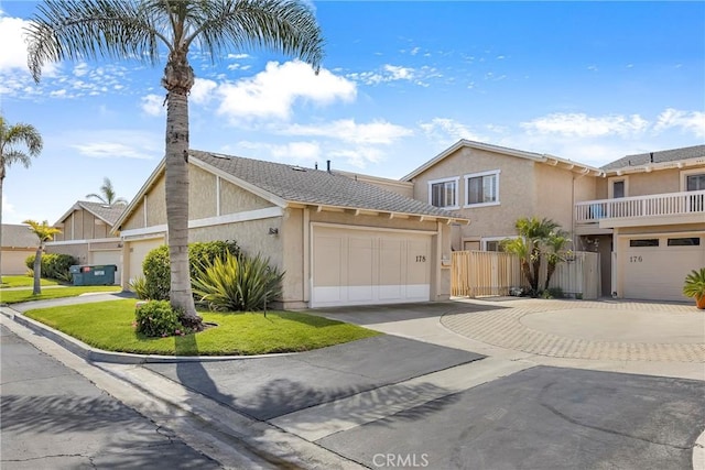 view of front of home featuring driveway, fence, an attached garage, and stucco siding