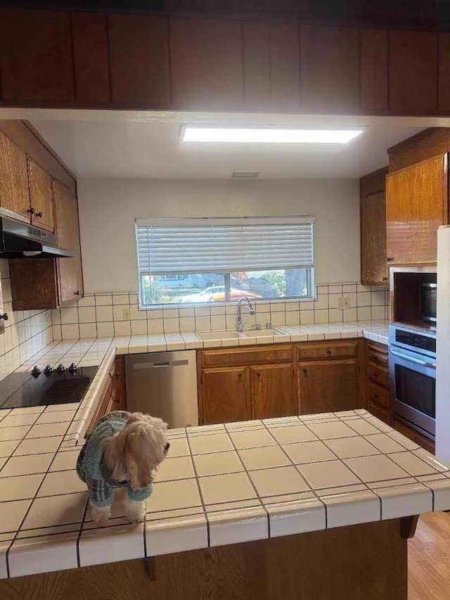 kitchen featuring stainless steel appliances, sink, and tile countertops