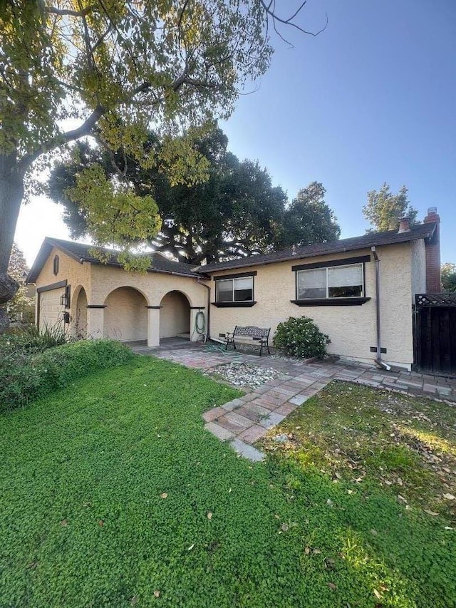 ranch-style house with a patio, a front lawn, and a garage