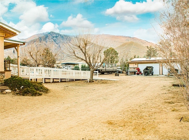 view of yard with a garage and a deck with mountain view