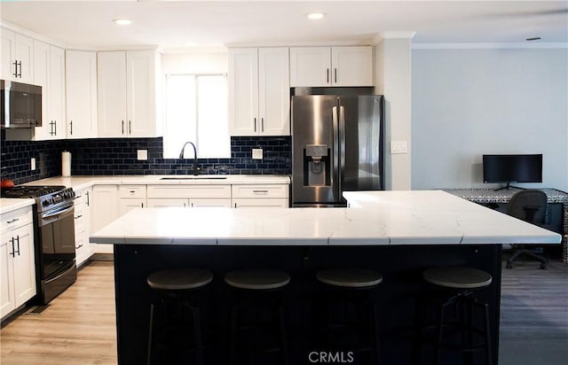 kitchen featuring a kitchen breakfast bar, sink, stainless steel fridge, and range with gas stovetop