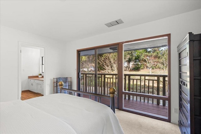 bedroom featuring light colored carpet, ensuite bathroom, and access to exterior