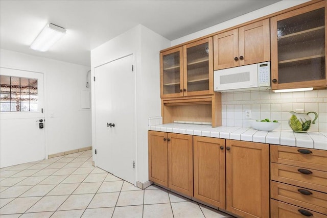 kitchen featuring tile countertops, light tile patterned floors, and backsplash