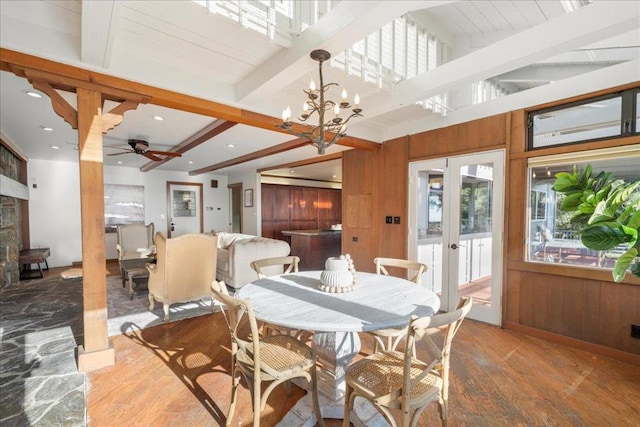 dining area with hardwood / wood-style floors, a notable chandelier, beam ceiling, and wood walls