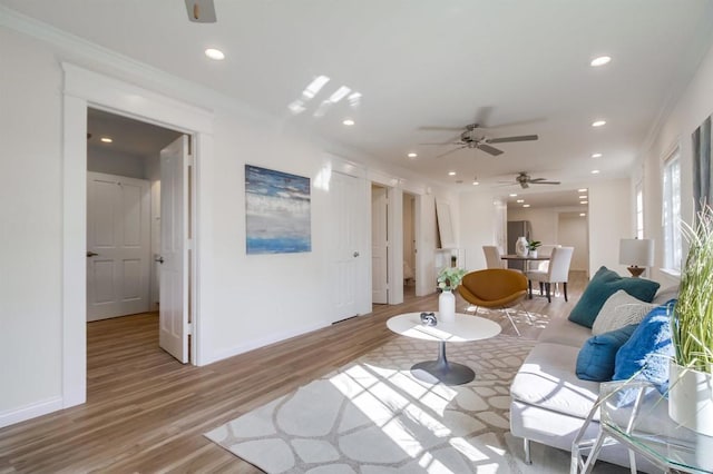 living room featuring crown molding, ceiling fan, and light hardwood / wood-style floors