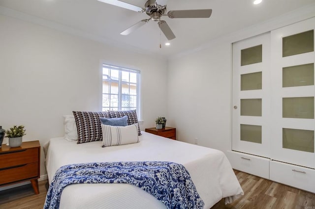 bedroom featuring ceiling fan, ornamental molding, and light wood-type flooring