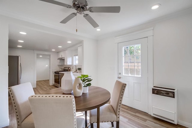 dining area with sink, heating unit, light hardwood / wood-style flooring, ornamental molding, and ceiling fan