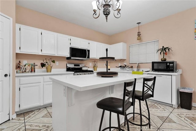 kitchen featuring a breakfast bar, dishwasher, white cabinets, hanging light fixtures, and range