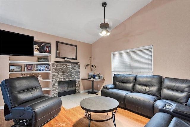 living room featuring vaulted ceiling, a fireplace, and light hardwood / wood-style flooring