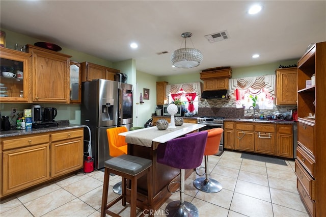 kitchen with pendant lighting, sink, appliances with stainless steel finishes, ventilation hood, and a kitchen bar