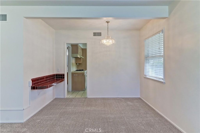 carpeted spare room featuring a notable chandelier