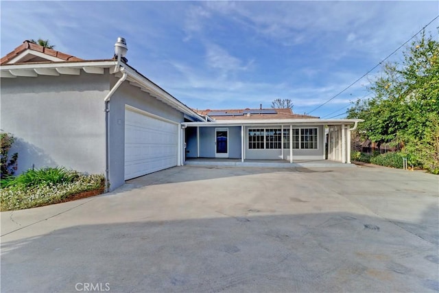 single story home with a garage and solar panels