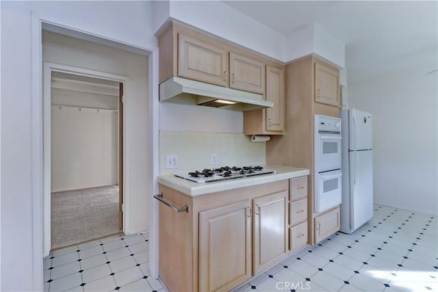 kitchen with white appliances, light brown cabinetry, and backsplash