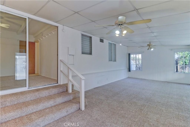 basement with ceiling fan, carpet, and a drop ceiling