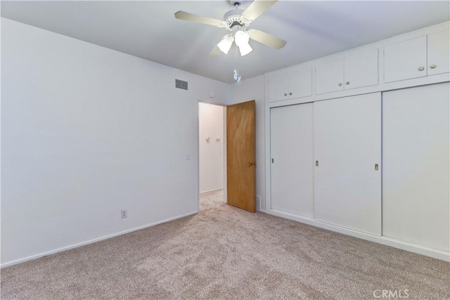 unfurnished bedroom with ceiling fan, a closet, and light carpet