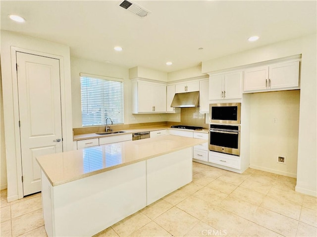 kitchen featuring sink, light tile patterned floors, appliances with stainless steel finishes, a kitchen island, and white cabinets