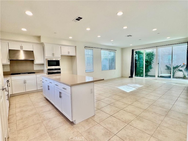 148 Stage, Irvine, CA 92618 - kitchen featuring white cabinetry, black stovetop, a kitchen island, built in microwave, and stainless steel oven