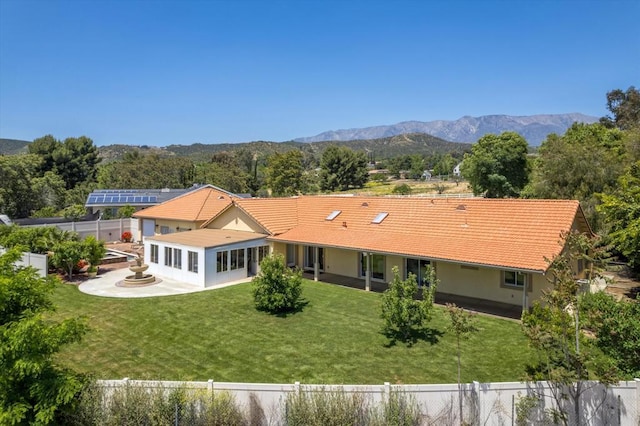 rear view of property with a mountain view, a patio area, and a lawn