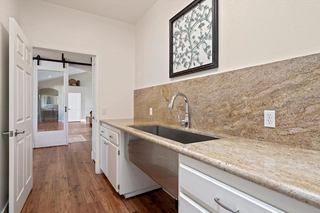 kitchen with sink, decorative backsplash, dark hardwood / wood-style floors, and a barn door