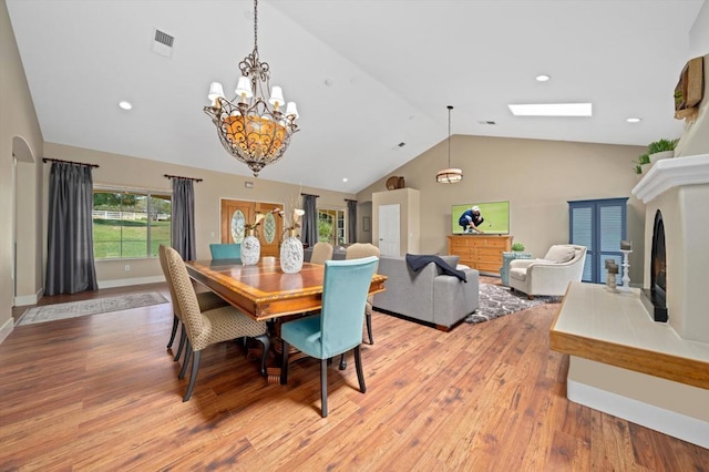 dining room featuring hardwood / wood-style floors and lofted ceiling with skylight