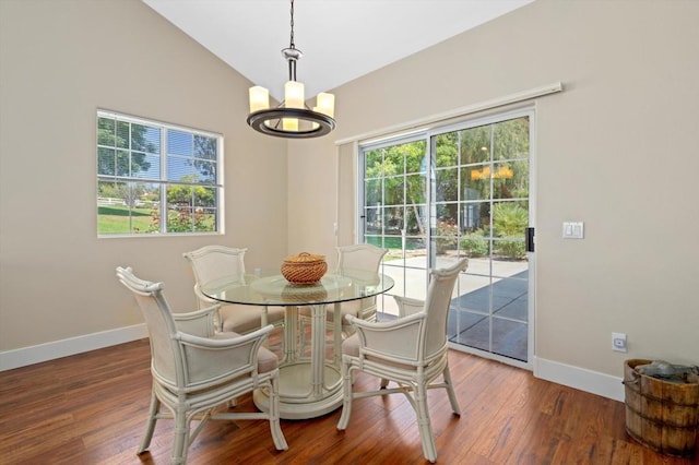 dining space with lofted ceiling, wood-type flooring, and a chandelier