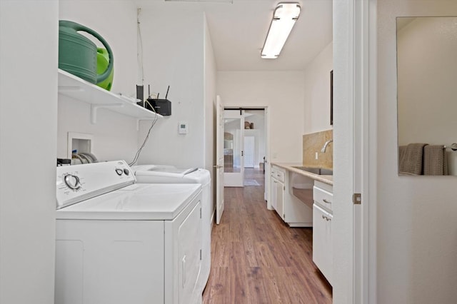 clothes washing area with hardwood / wood-style flooring, a barn door, and washer and dryer