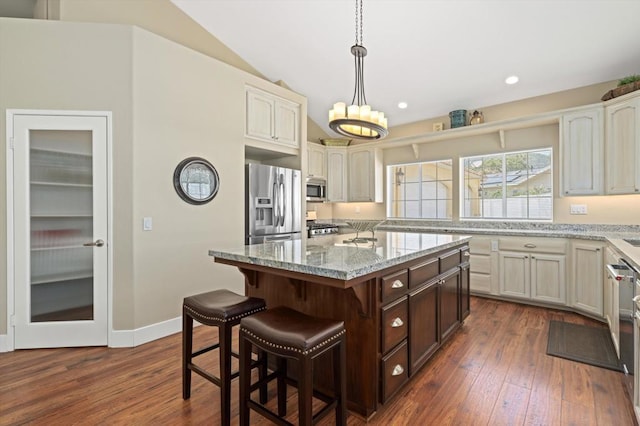 kitchen featuring dark hardwood / wood-style floors, decorative light fixtures, a center island, stainless steel appliances, and light stone countertops