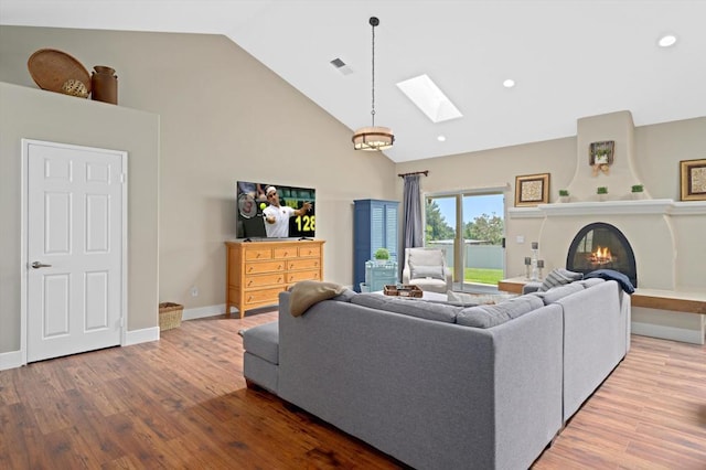 living room with hardwood / wood-style floors, high vaulted ceiling, and a skylight