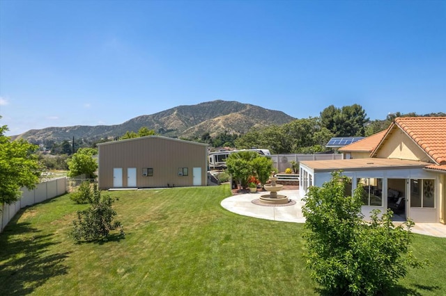 back of property with a mountain view, a lawn, and a patio