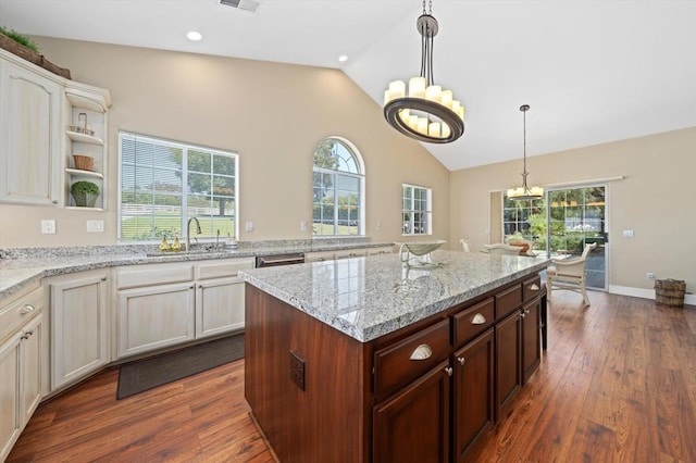 kitchen featuring sink, a center island, dark hardwood / wood-style flooring, a notable chandelier, and light stone countertops