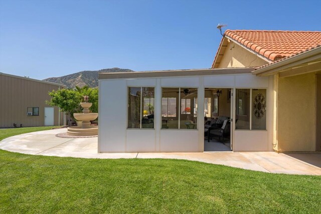 rear view of house with a yard, a mountain view, and a patio