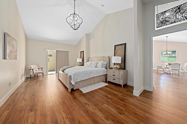 bedroom with a notable chandelier, wood-type flooring, and high vaulted ceiling