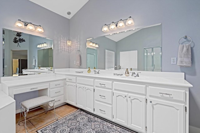 bathroom with vanity, tile patterned flooring, vaulted ceiling, and walk in shower