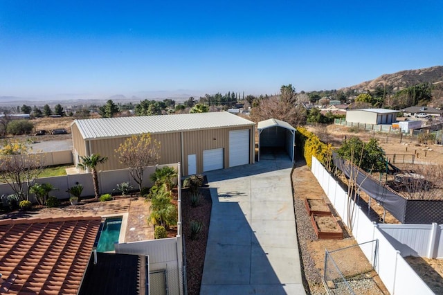 exterior space featuring a fenced in pool, a garage, an outdoor structure, and a mountain view