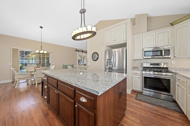 kitchen featuring stainless steel appliances, lofted ceiling, an inviting chandelier, and decorative light fixtures