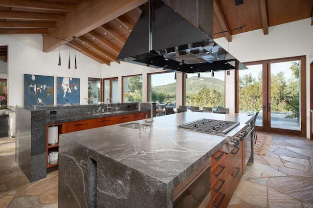 kitchen featuring sink, range hood, an island with sink, and beamed ceiling