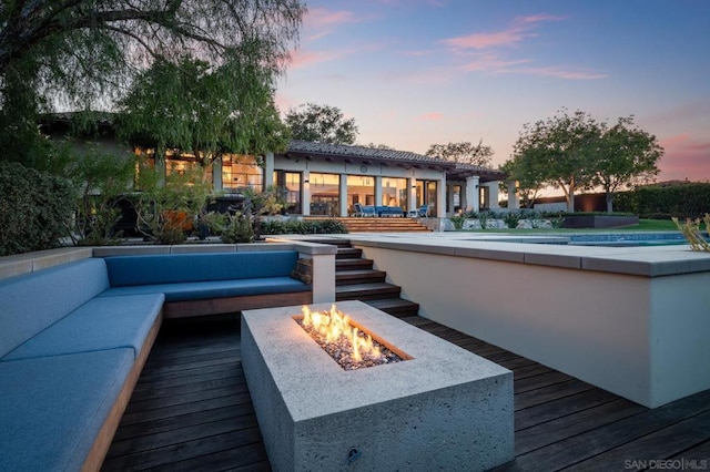 deck at dusk featuring an outdoor living space with a fire pit