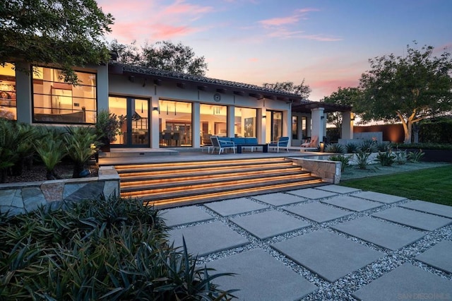 back house at dusk featuring outdoor lounge area and a patio area