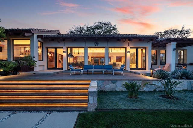 back house at dusk featuring a wooden deck and an outdoor hangout area