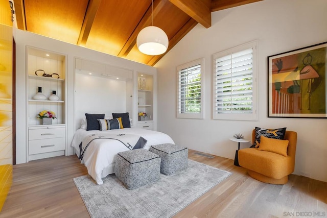 bedroom with lofted ceiling with beams and light wood-type flooring