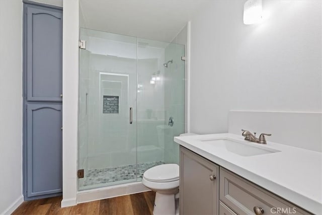 bathroom with vanity, a shower with door, toilet, and hardwood / wood-style floors