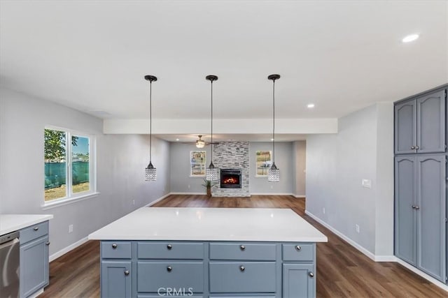 kitchen with stainless steel dishwasher, a large fireplace, pendant lighting, and dark hardwood / wood-style flooring