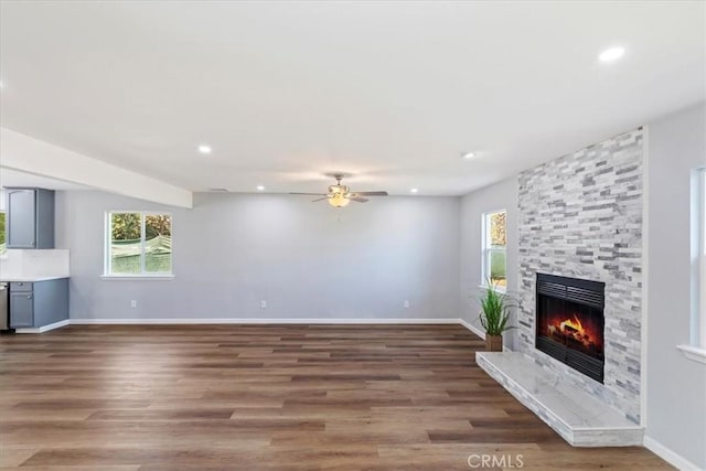 unfurnished living room featuring a fireplace, ceiling fan, and dark hardwood / wood-style floors