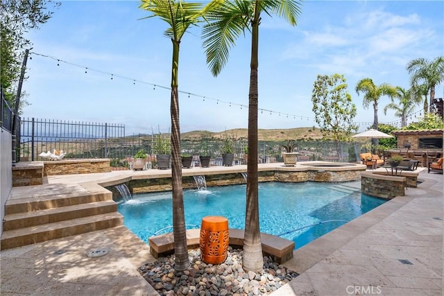 view of swimming pool with an in ground hot tub, pool water feature, a mountain view, and a patio