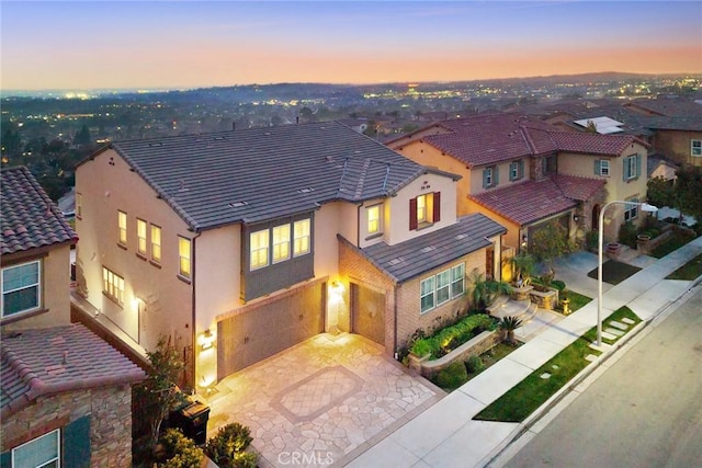 view of front of home with stucco siding, driveway, an attached garage, and a tiled roof