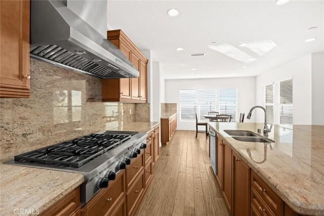 kitchen featuring sink, tasteful backsplash, light hardwood / wood-style flooring, stainless steel gas stovetop, and exhaust hood